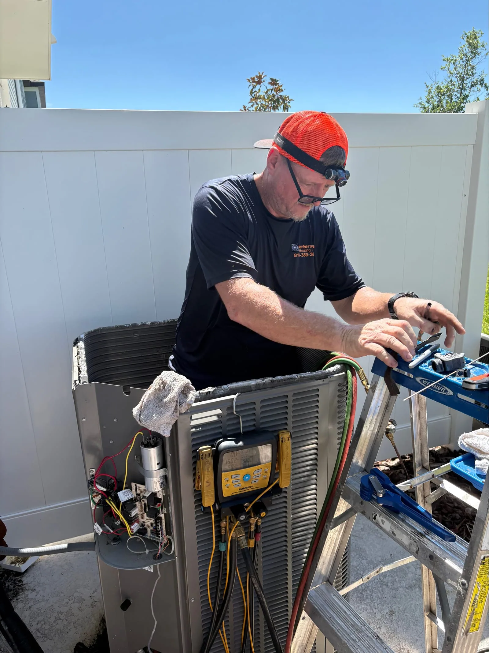 Parkersons HVAC technician performing repairs on a residential air conditioner unit